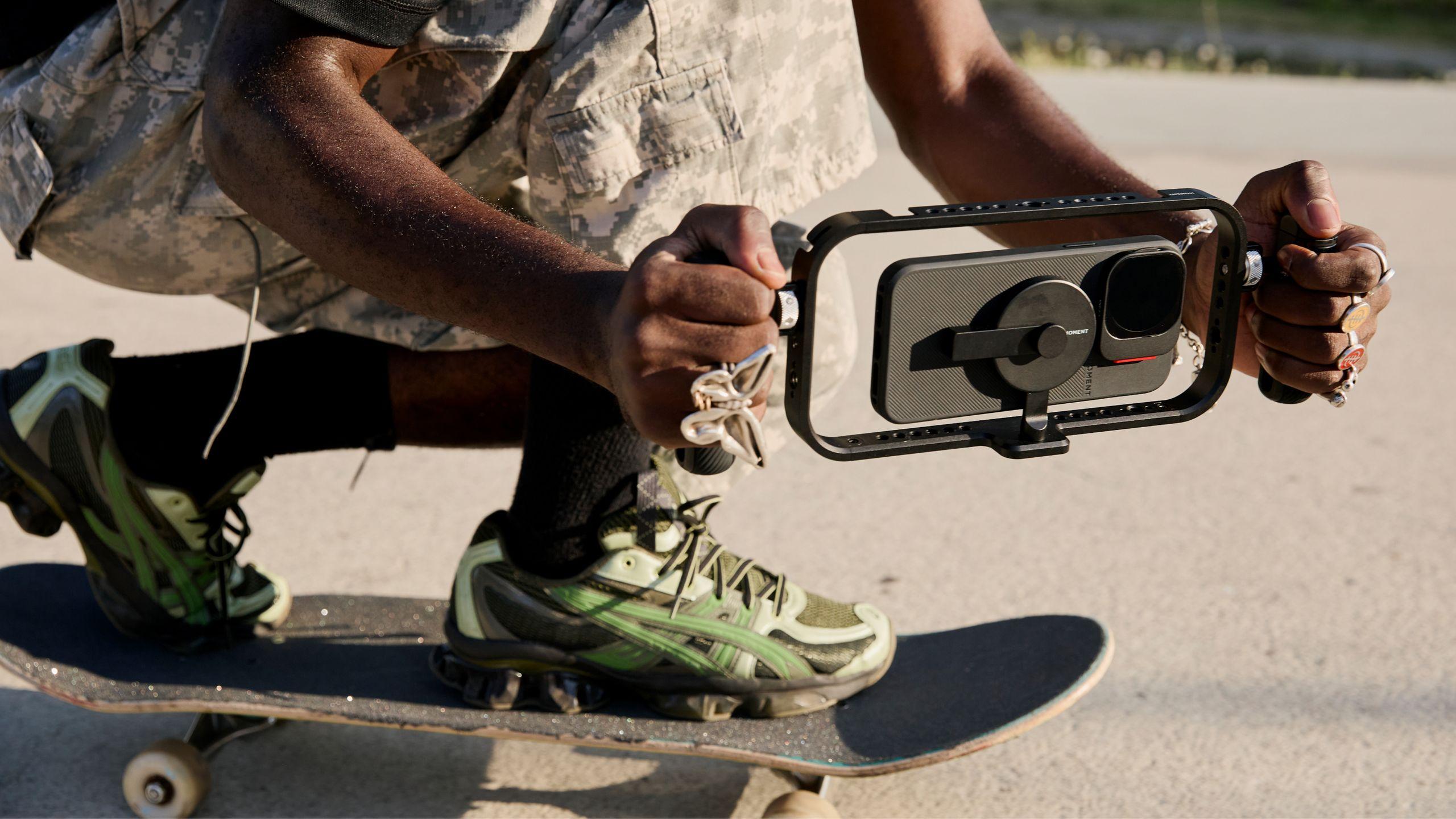 Hand holding iPhone 16 with a mobile filmmaker cage with an on-camera shotgun microphone for footage.